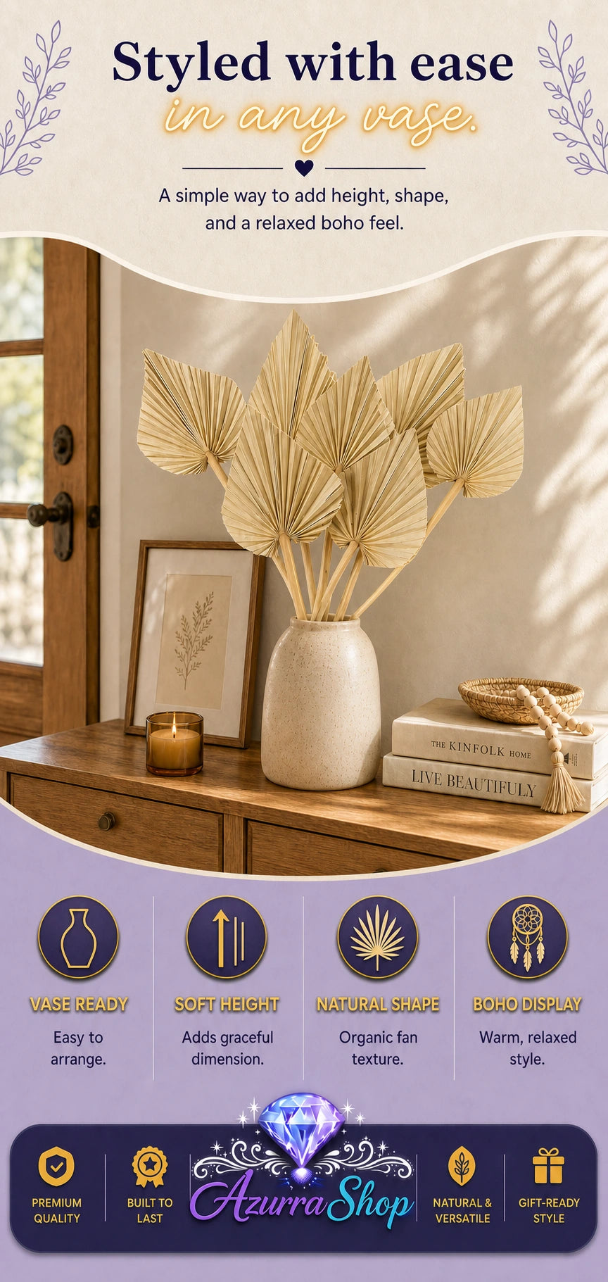 Dried palm fan leaves in a speckled cream vase on a wooden dresser styled with a picture frame, lit candle, books, and a woven bowl with tassel beads