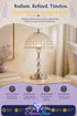 A crystal table lamp with a polished silver base and a dome-shaped crystal shade, displayed on a wooden side table in a softly lit living room. The image includes promotional text at the top and a purple feature banner at the bottom with the brand name Azurra Shop.