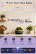 Black script wall decal reading "The Kitchen is the Heart of the Home" mounted on a beige kitchen wall above a countertop with potted plants and wooden utensils, with a purple graphic footer showing feature icons and the Azurra Shop logo.