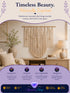 Marketing graphic for a white macrame tassel wall hanging on a wood dowel, styled above a console table in a warm bedroom setting.