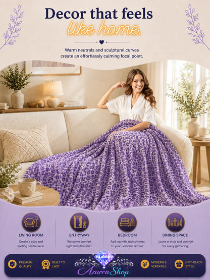 Lavender leopard print fleece blanket draped over a beige sofa in a living room, with an Azurra Shop promotional banner