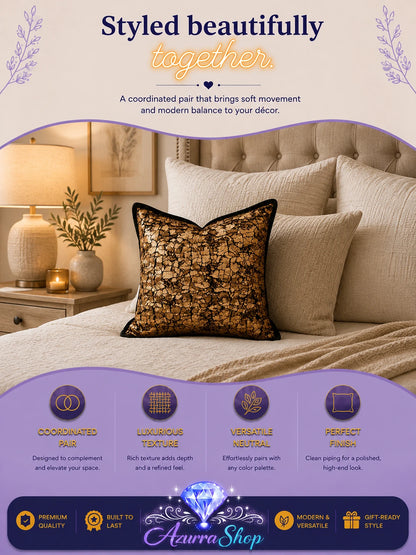 Black and gold lace-patterned throw pillow styled on a bed with beige linen bedding and matching pillows