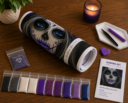 Blue-Eyed Sugar Skull Woman Diamond Painting Kit – flat lay on warm dark wood surface showing blue-eyed sugar skull woman canvas rolled and labeled "Brilliance You Create" with design visible showing glowing blue eyes and purple swirls, one sealed bag labeled "Extra Drills", 10 individual sealed bags of round resin drills in black, dark charcoal, gray, white, cream, dark purple, medium purple, light lavender, royal blue, and teal tones, black tweezers and purple applicator pen on a white hexagonal tray, pur