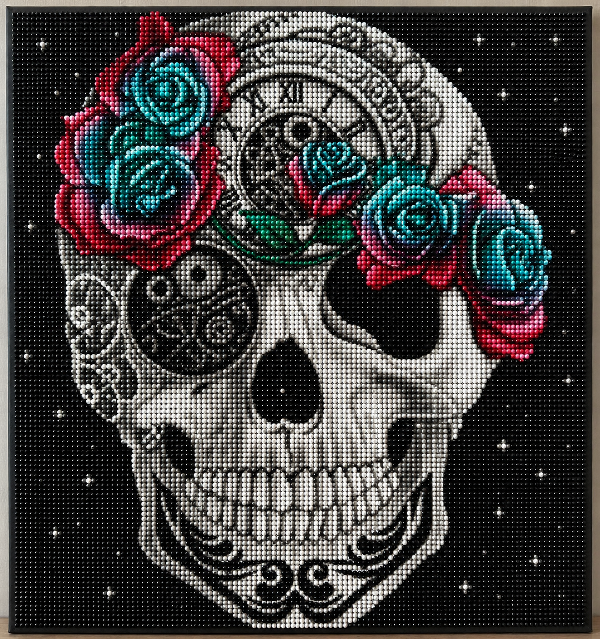 Steampunk Rose Crown Skull Diamond Painting Kit – completed 5D diamond art close-up featuring a detailed white sugar skull with intricate black filigree patterns, a Roman numeral clock face on the forehead, and a lush crown of teal and red roses on a black starry background
