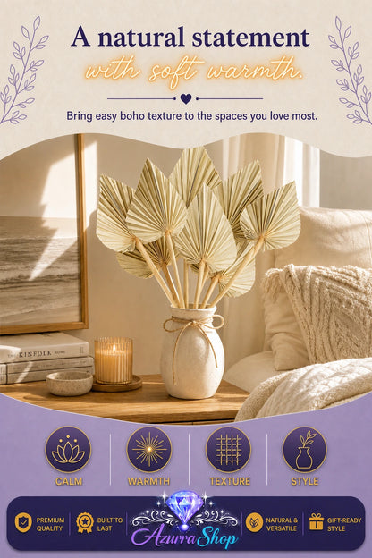Dried palm fan leaves tied with twine in a speckled cream vase on a wooden nightstand next to a lit candle, ocean art print, and a knit throw