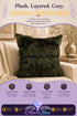 Dark olive green faux-fur throw pillow with folded texture, styled on a beige armchair; promotional text reads "Plush. Layered. Cozy."