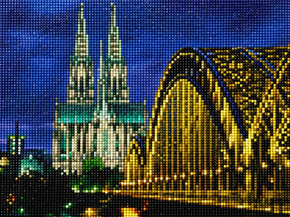 Finished Cologne Cathedral diamond painting kit artwork with the twin Gothic spires lit up at night above the golden bridge and river | Azurra Shop