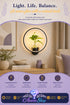 Black circular wall sconce with a built-in glass plant holder and a small potted green plant, mounted on a beige wall above a wooden console table, with a header graphic reading &